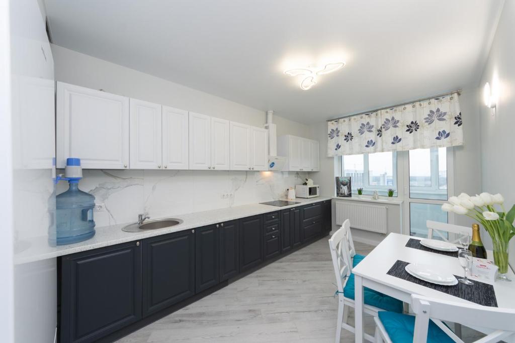 a kitchen with black and white cabinets and a table at Красивая 1 комнатная квартира с балконом на Теремках 252 in Kyiv