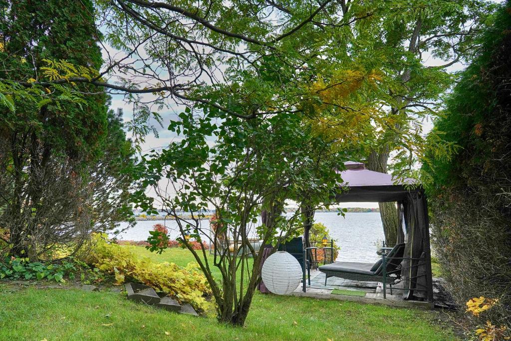 a chair sitting under a gazebo next to the water at Gîte le 308 Chambre bord de l'eau oka in Oka