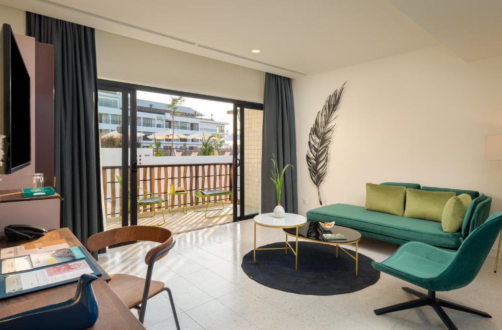a living room with a green couch and a balcony at The Aviary Hotel in Siem Reap