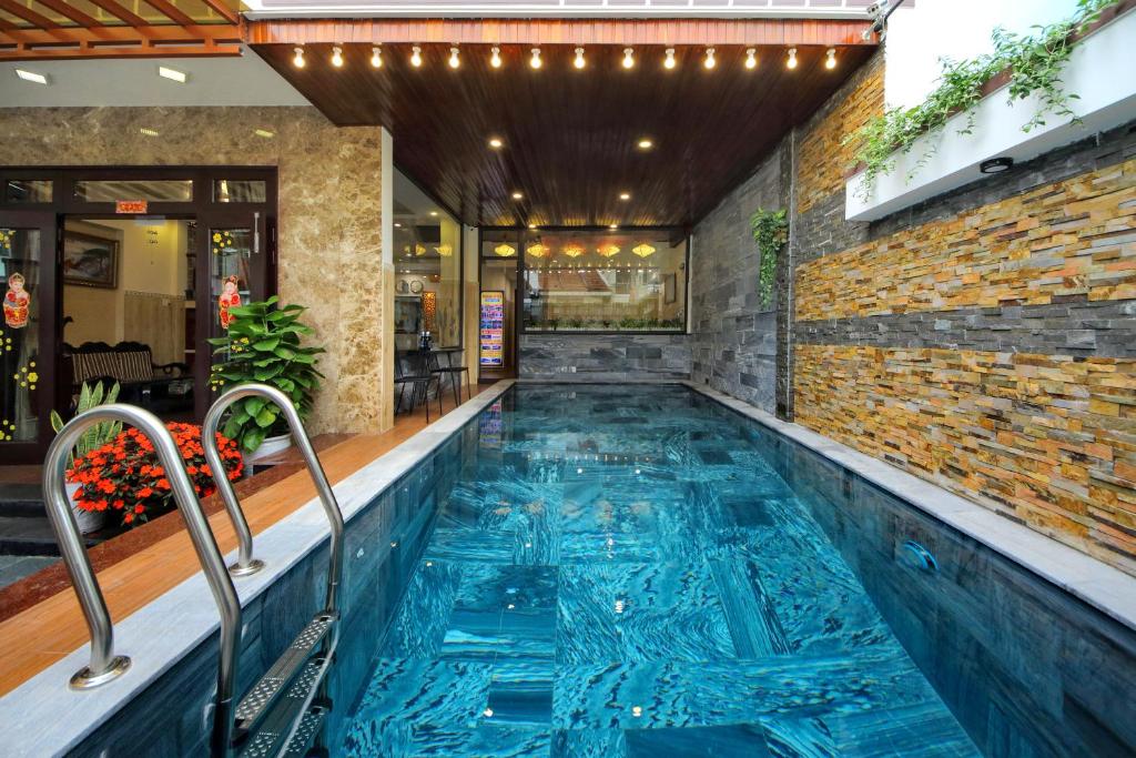 a swimming pool in a building with a brick wall at Homestay May Trang in Hoi An