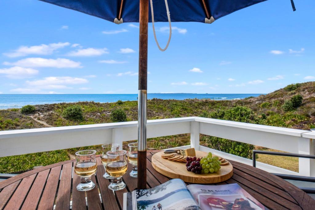 einen Tisch mit Weingläsern und einen Teller mit Essen in der Unterkunft Oceanside Bach - Mount Maunganui Holiday Home in Mount Maunganui