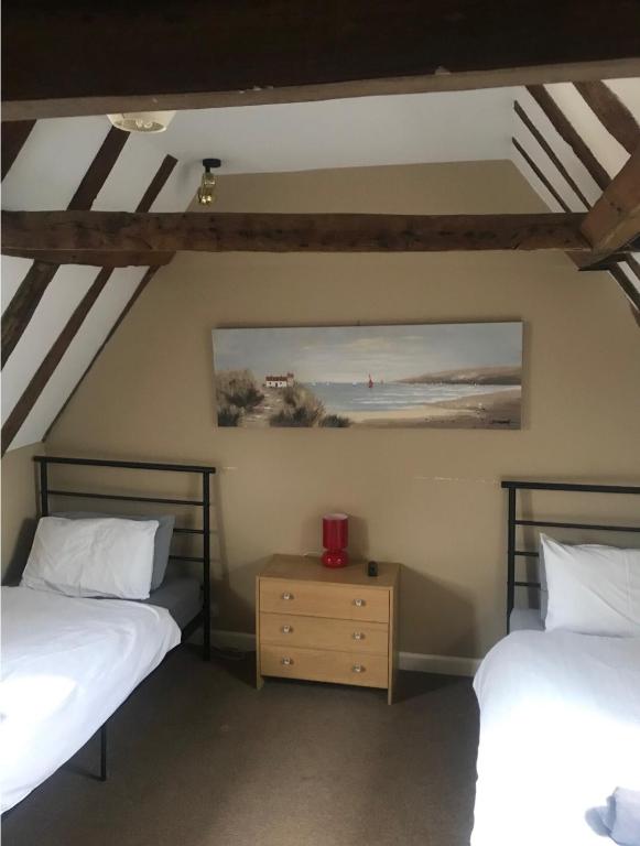 a bedroom with two beds and a table with a picture on the wall at 18th Century Character apartment. in Ipswich