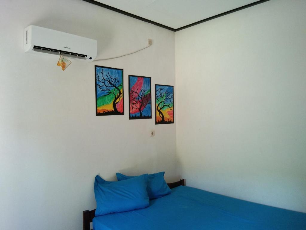 Bett in einem Zimmer mit Gemälden an der Wand in der Unterkunft Latansa inn in Karimunjawa