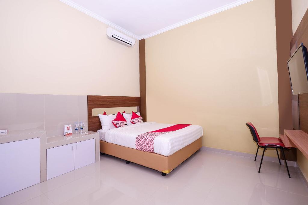 ein Schlafzimmer mit einem Bett und einem roten Stuhl in der Unterkunft OYO 1506 Shabrina 2 Syariah in Solo