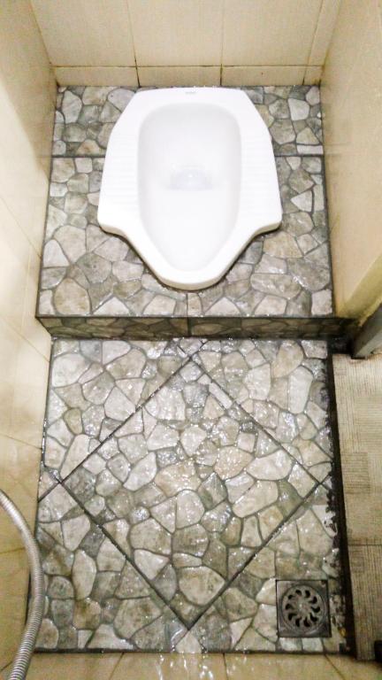 e bagno con servizi igienici bianchi su un pavimento in pietra. di Ngampilan Backpacker Hostel a Yogyakarta