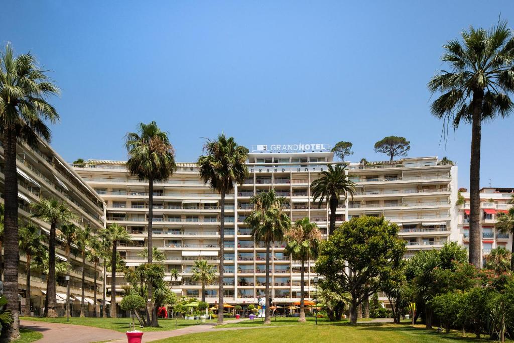 un gran edificio con palmeras delante en Appartements Croisette Grand Hôtel en Cannes