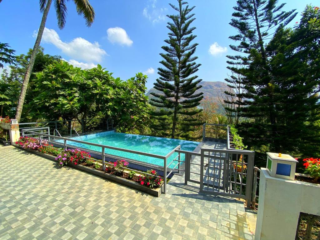 a swimming pool with flowers and trees at Sceva's Garden Home in Munnar