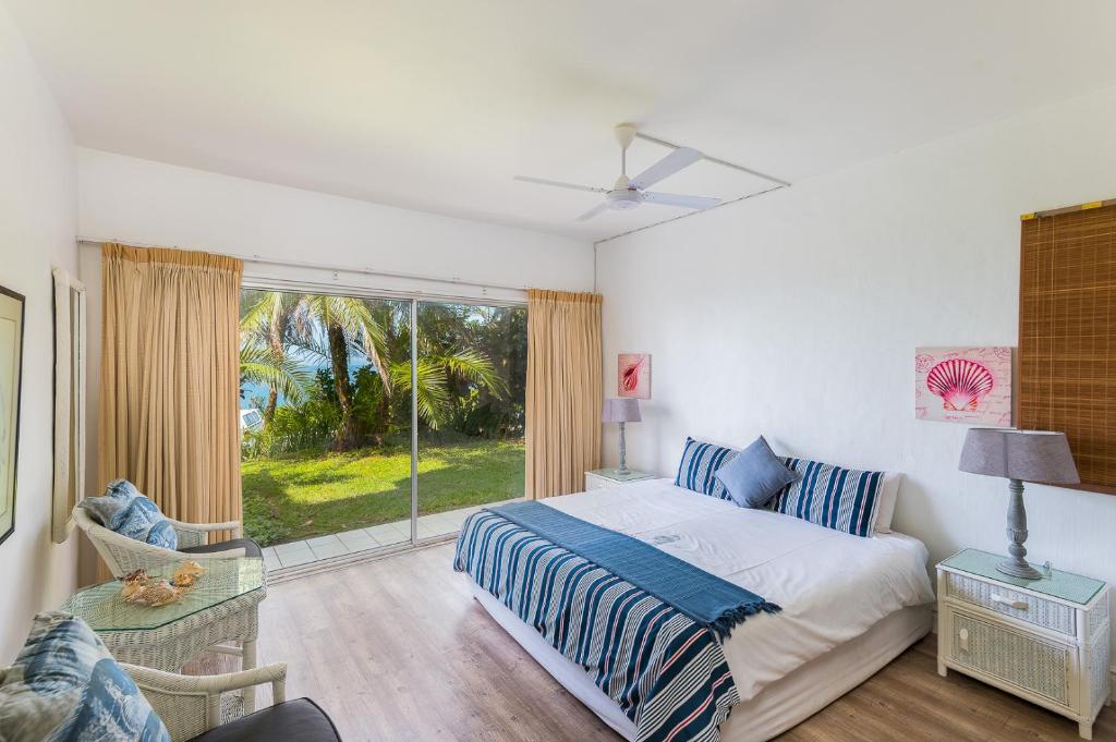 a bedroom with a bed and a large window at Santorini - Pyrgos 15 in Ballito