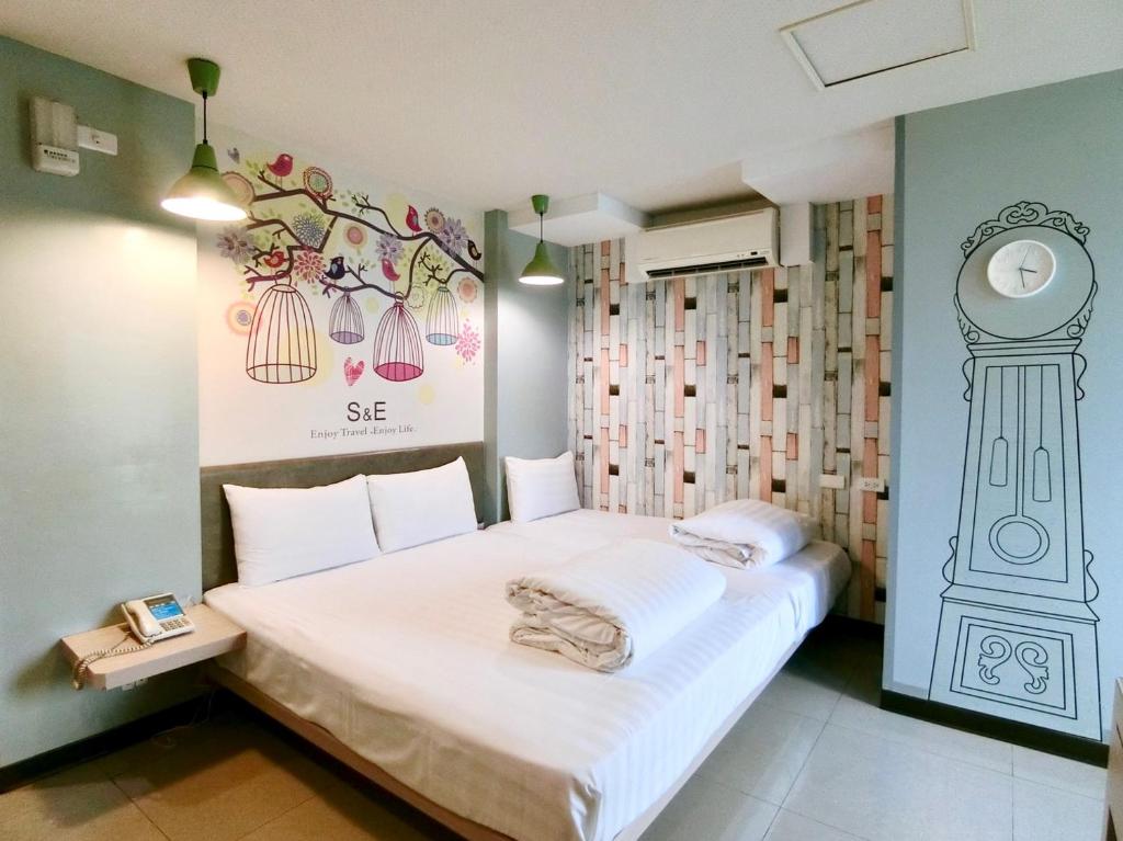 a bedroom with a bed and a clock on the wall at S&amp;E Hotel in Tainan