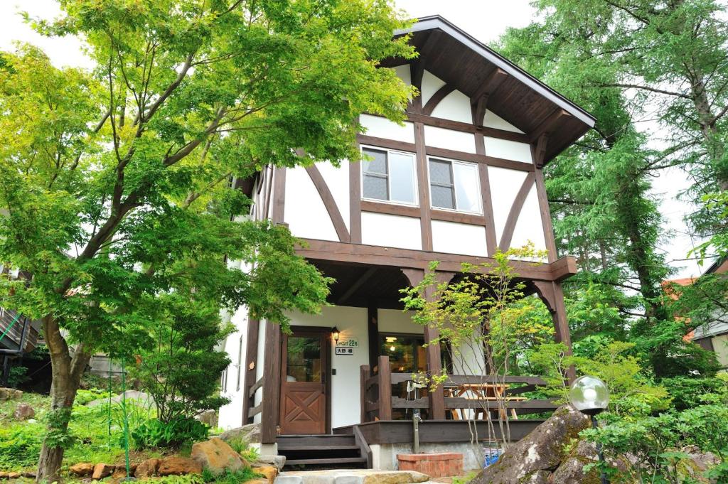 ein winziges Haus im Wald mit einer umlaufenden Veranda in der Unterkunft Cottage All Resort Service / Vacation STAY 8445 in Inawashiro