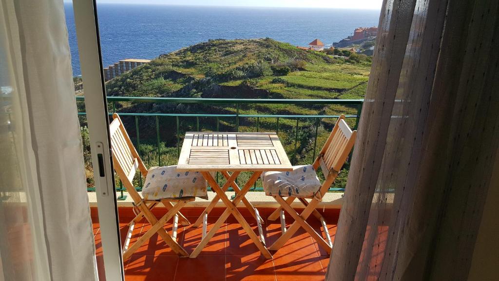 einen Tisch und Stühle auf einem Balkon mit Meerblick in der Unterkunft Reis Magos View in Caniço
