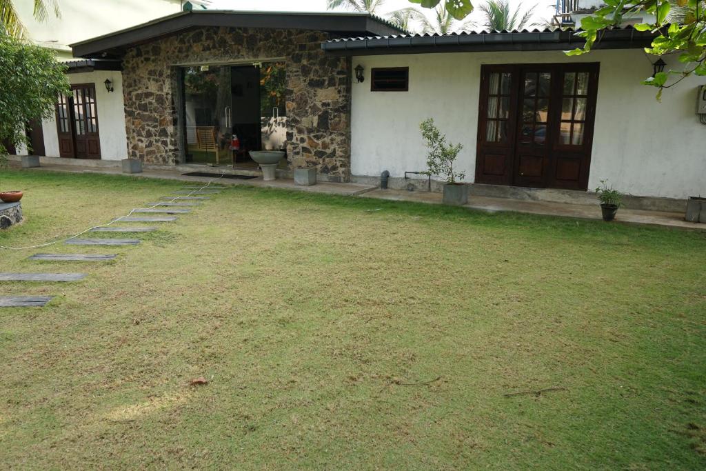 a house with a grass yard in front of it at Thiranagama Beach Hotel in Hikkaduwa