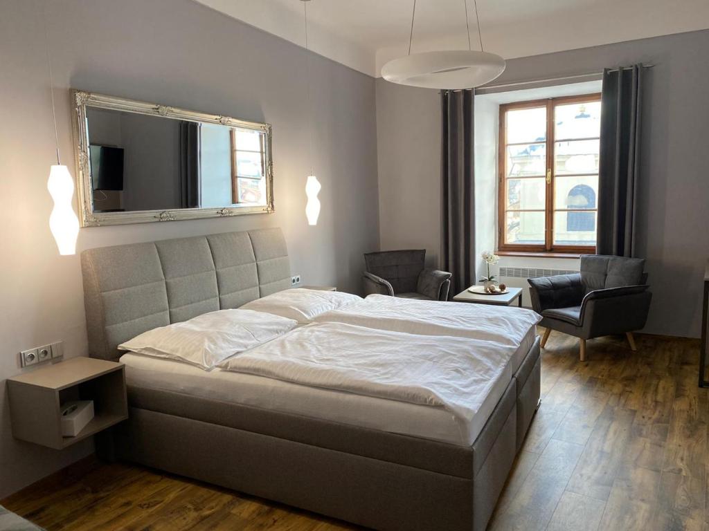 um quarto com uma cama, uma televisão e uma cadeira em Hotel Gurman em Horšovský Týn