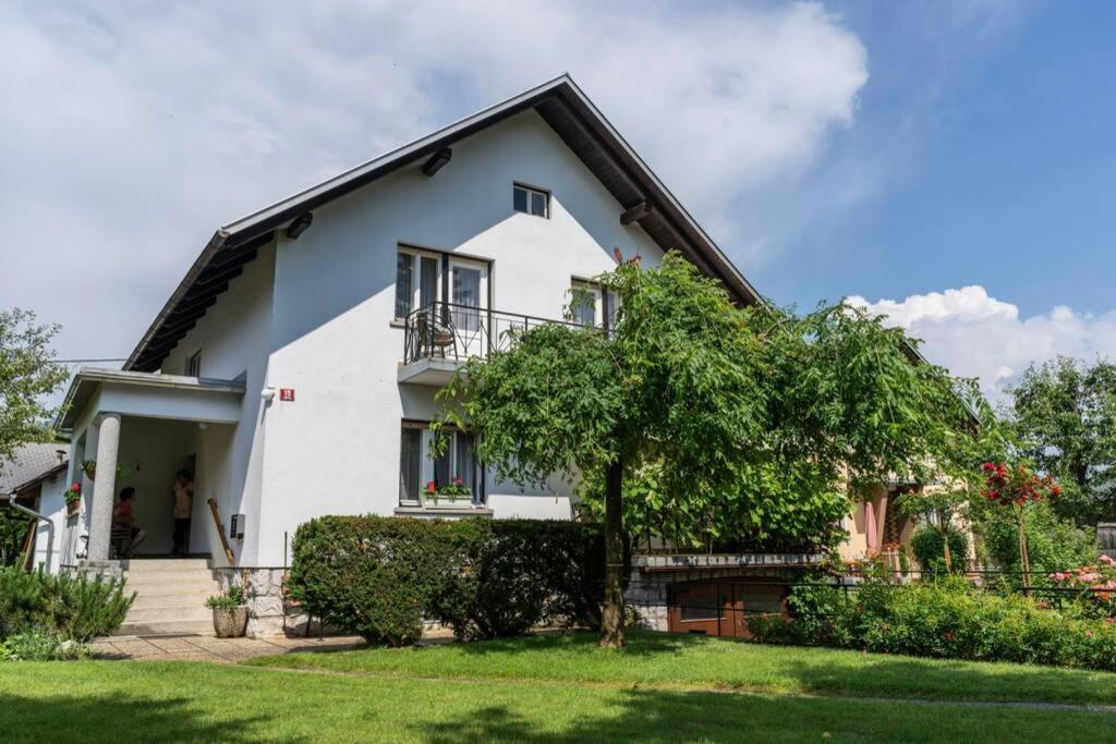 a white house with a tree in the yard at APARTMA JANŠA in Bled
