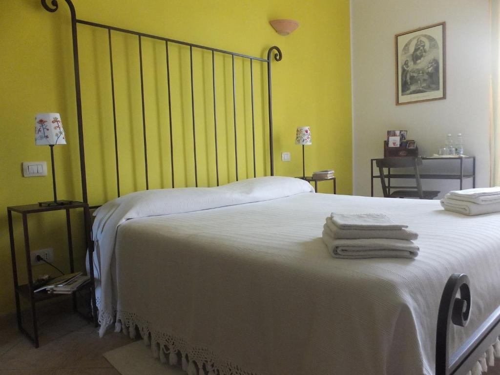 a bedroom with a bed with white sheets and yellow walls at Cascina Antonini in Foligno