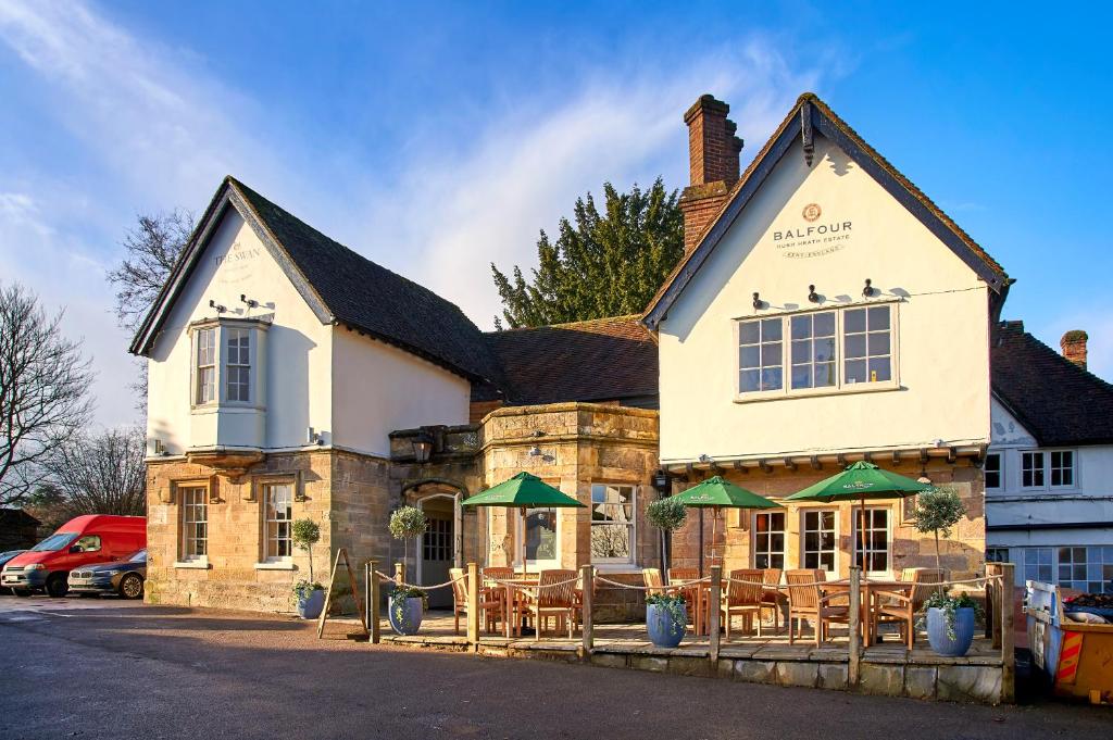 un edificio con mesas y sombrillas verdes delante de él en The Swan at Forest Row en Forest Row