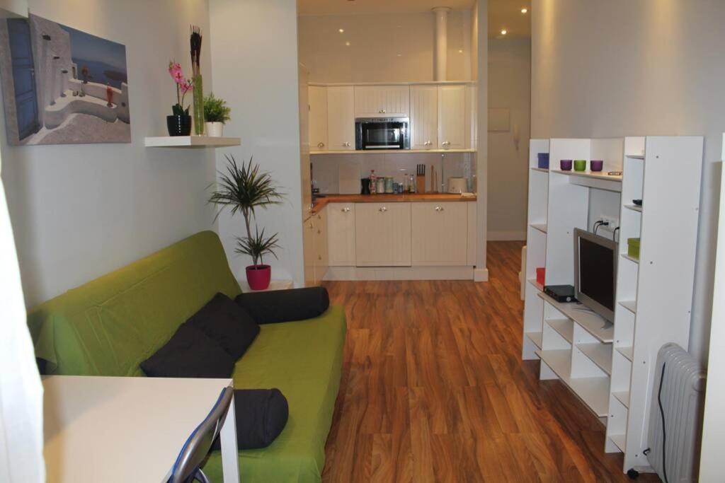 uma sala de estar com um sofá verde e uma cozinha em Bonito apartamento Cádiz centro em Cádiz