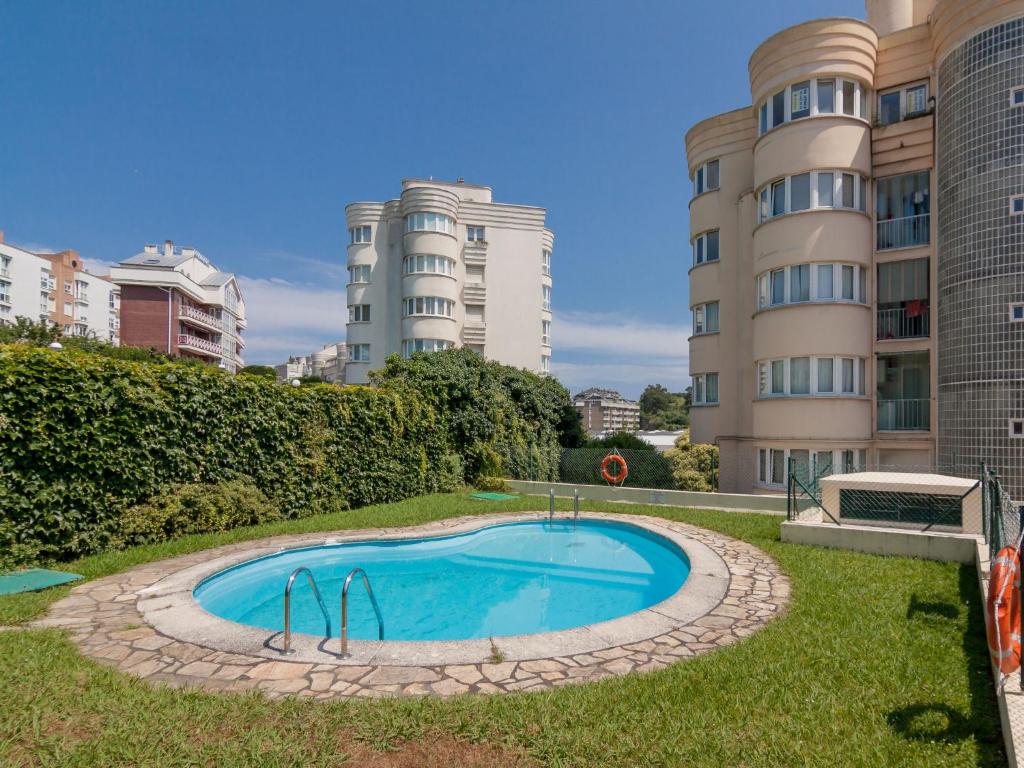 a swimming pool in the grass next to some buildings at Apartment Rico by Interhome in Castro-Urdiales