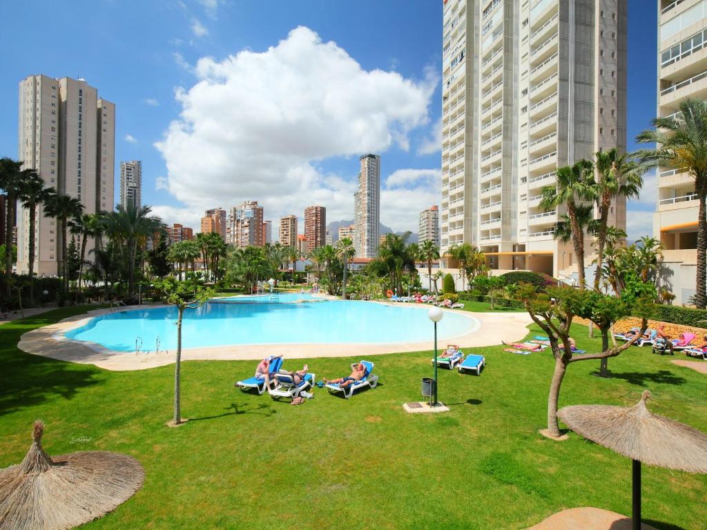 a group of people sitting in lawn chairs by a pool at Apartment Los Gemelos-2 by Interhome in Benidorm