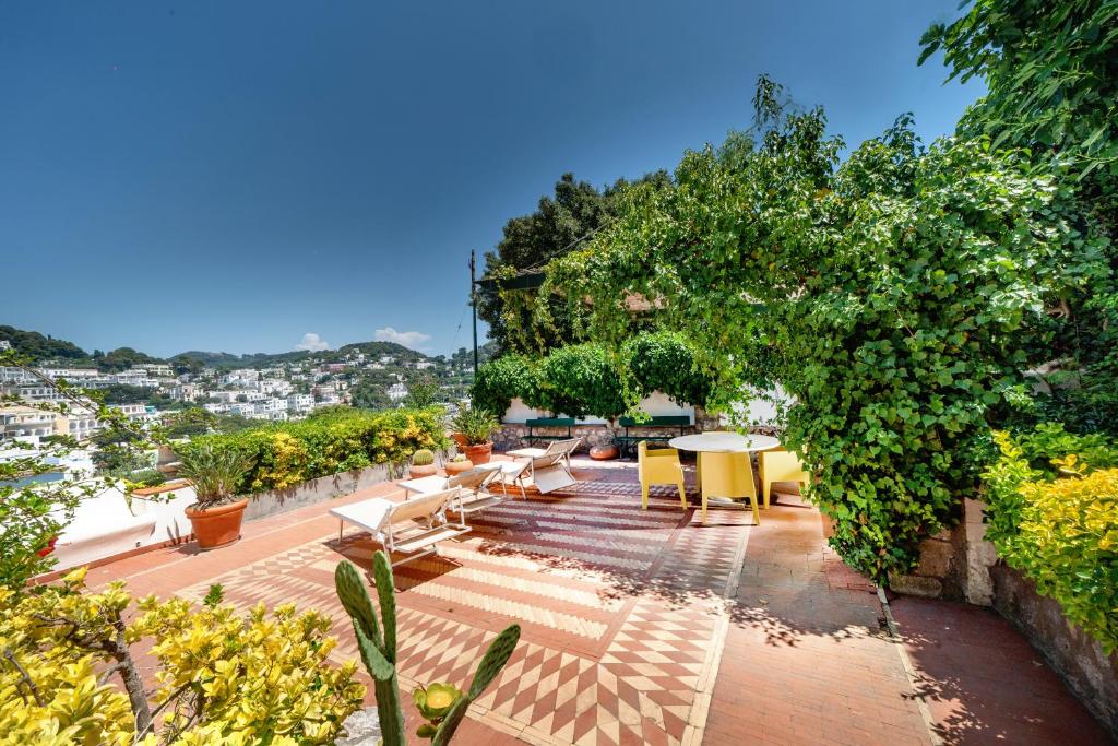 a patio with tables and chairs and a tree at Charming Villa in Capri