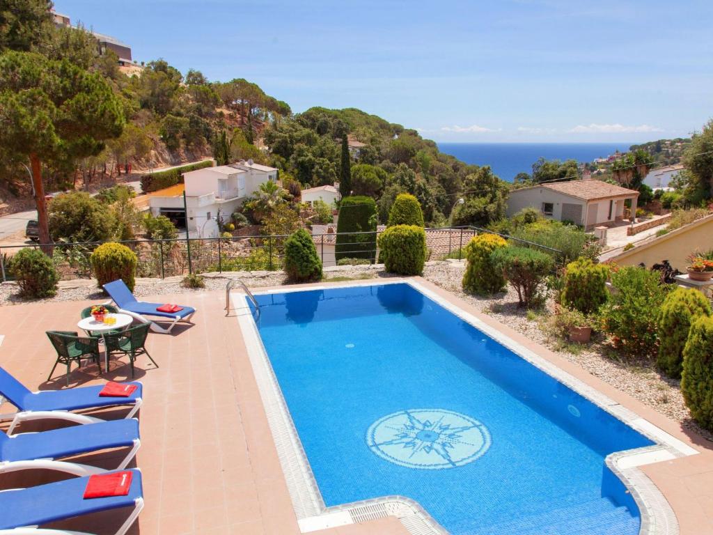 uma piscina com cadeiras e uma mesa e o oceano em Holiday Home Cala Llorell by Interhome em Tossa de Mar