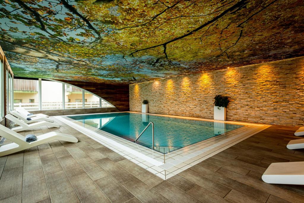 a pool in a building with a tree ceiling at L'Orée du Bois in Vittel