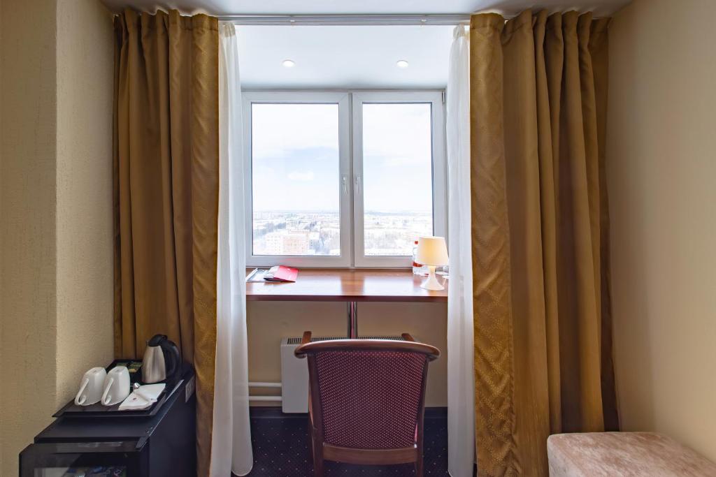 a room with a desk and a window with a table and a chair at AZIMUT Hotel Kemerovo in Kemerovo