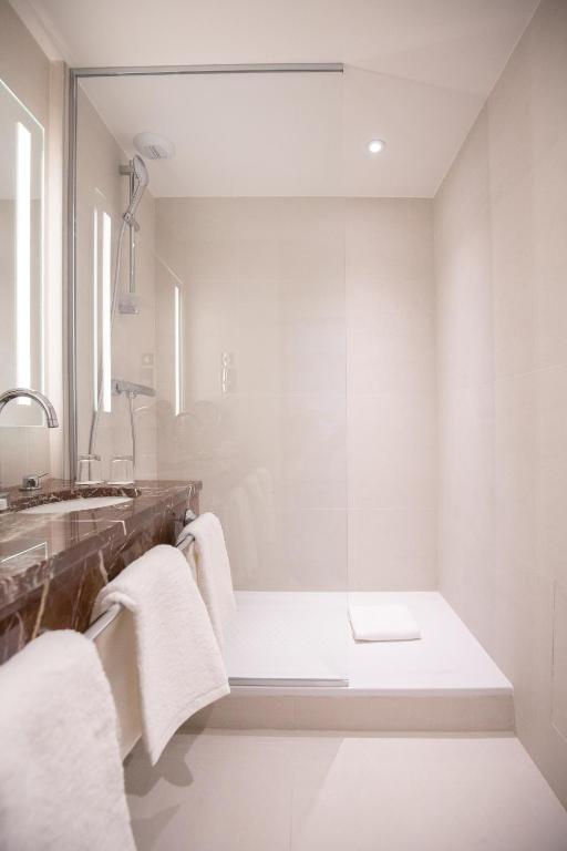 a bathroom with white towels and a sink at Hôtel Alfred Sommier in Paris