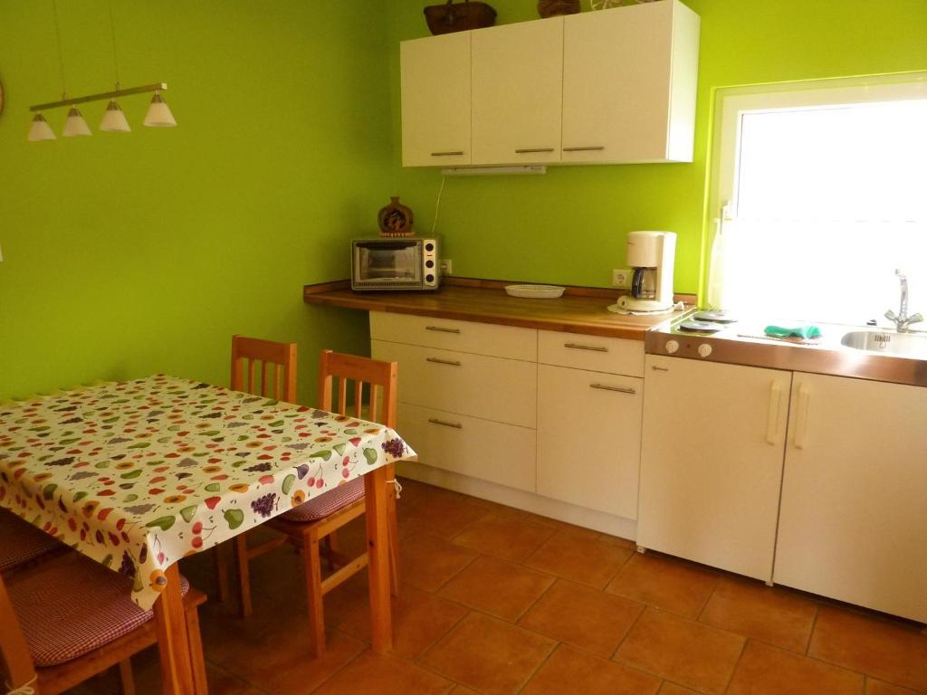 a kitchen with green walls and a table and a microwave at Ferienwohnungen An den Linden in Burg