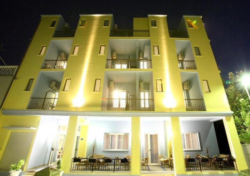 a large yellow building with tables in front of it at Hotel Miramare in Marotta
