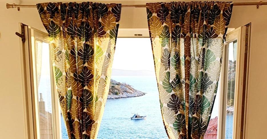 - une fenêtre avec des rideaux offrant une vue sur l'océan dans l'établissement Apartman Šime, à Tribunj