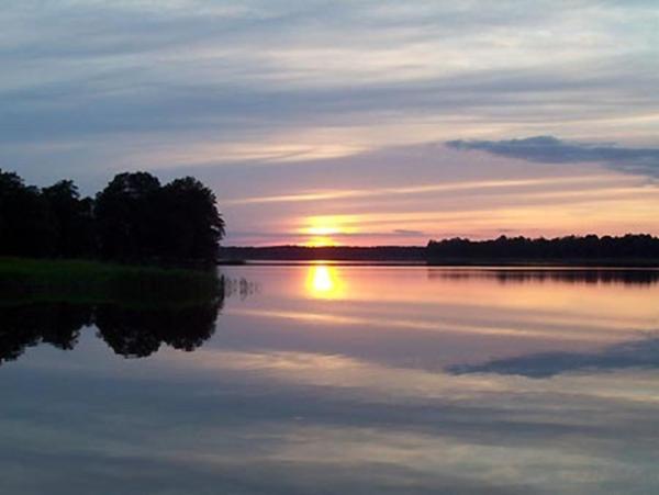 una puesta de sol sobre un gran lago con puesta de sol en Pokoje u Gosi, en Węgorzewo
