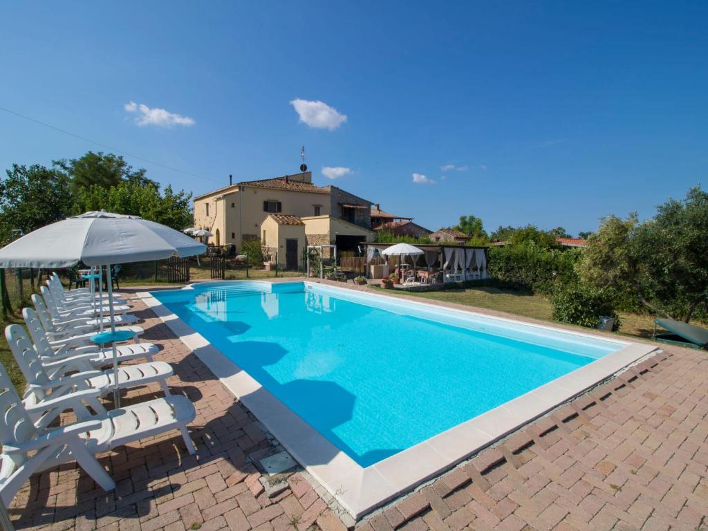 a swimming pool with chairs and an umbrella at Apartment Il Secondo-3 by Interhome in Bibbona