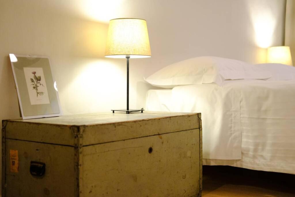 een lamp bovenop een houten kist naast een bed bij Cute and charming suite in Florence