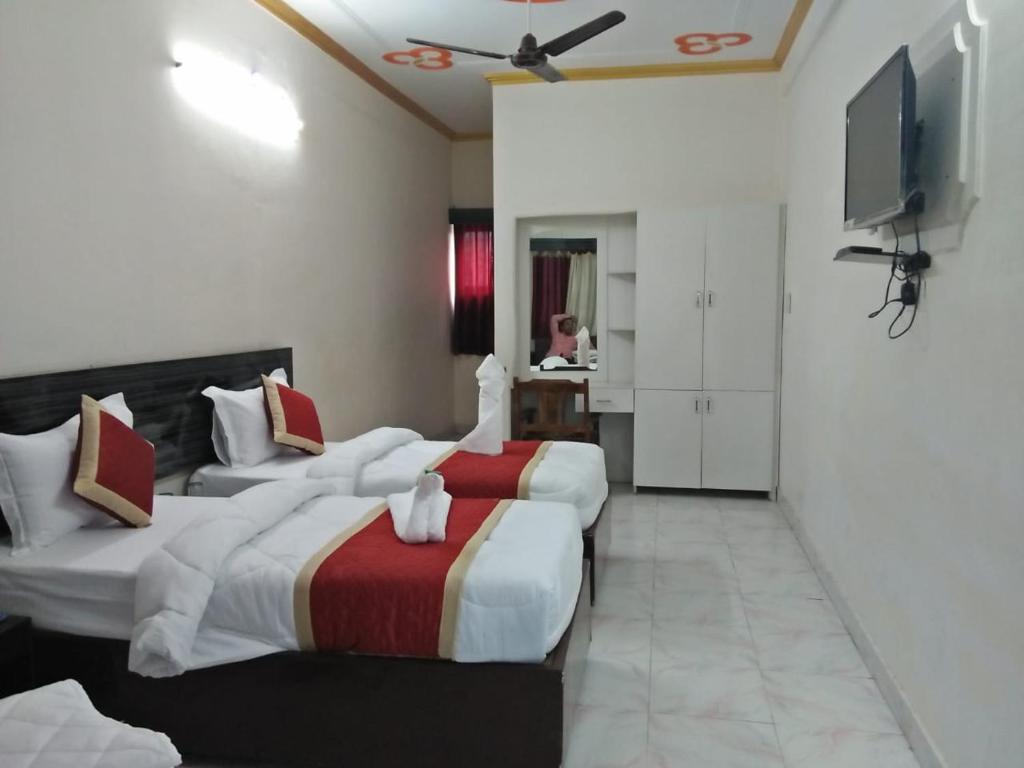 um quarto de hotel com duas camas e uma televisão de ecrã plano em HOTEL BUDDHA em Kushinagar