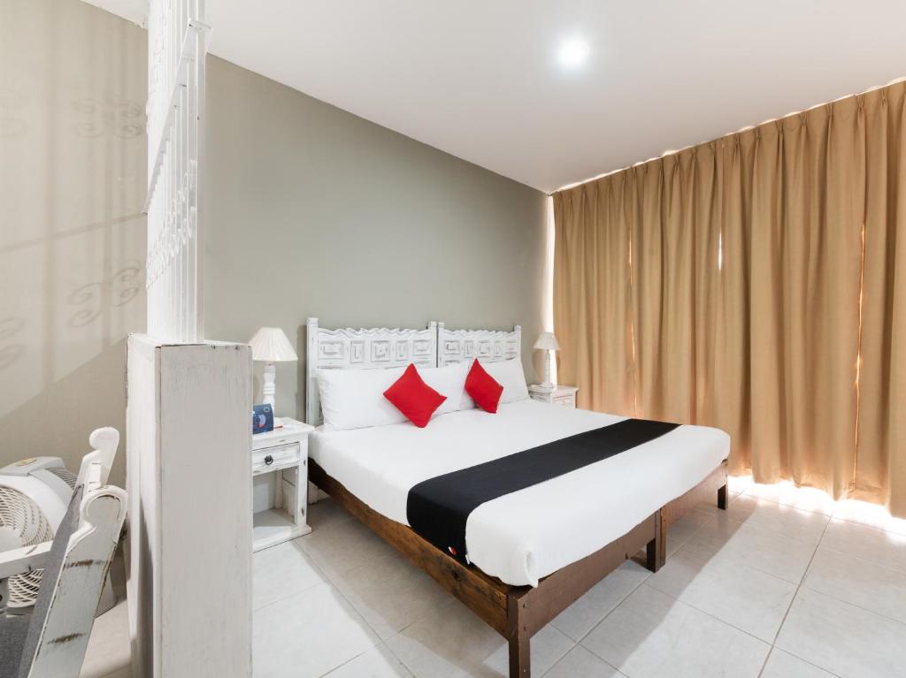 um quarto com uma grande cama branca com almofadas vermelhas em Suites Internacional em Guadalajara