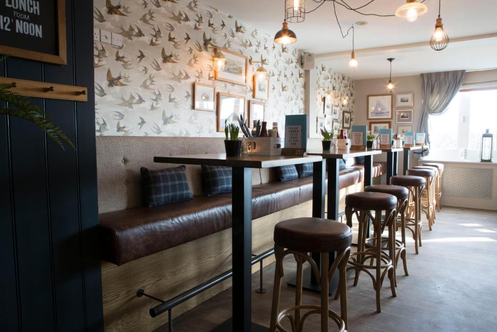 a bar with brown leather seats and a row of bar stools at Seacroft in Holyhead