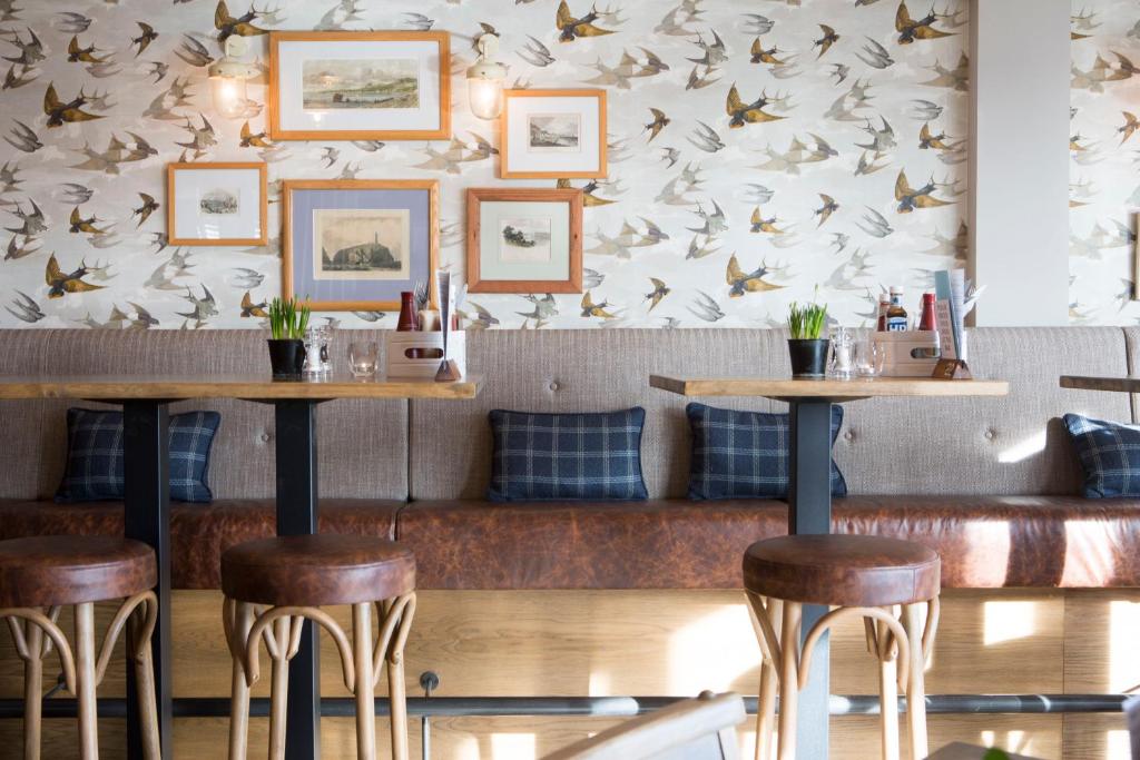 a restaurant with bar stools and a wall with birds at Seacroft in Holyhead