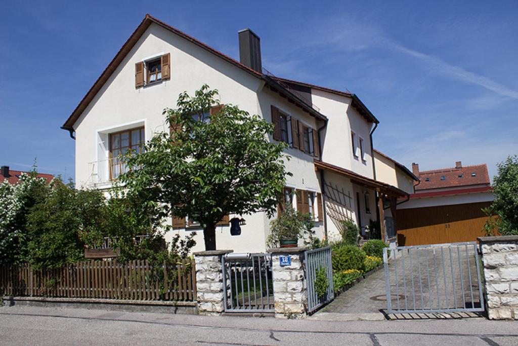 a white house with a fence and a tree at Ferienwohnung "Müller" in Beilngries