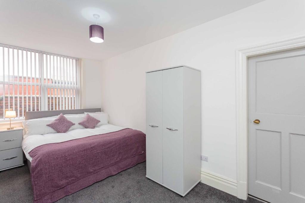 a white bedroom with a bed and a cabinet at Cherry Property - Plum Suite in Blackpool