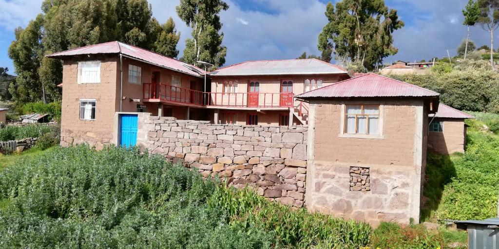 una casa en la parte superior de una pared de piedra en Taquile Hospedaje Mario en Huillanopampa