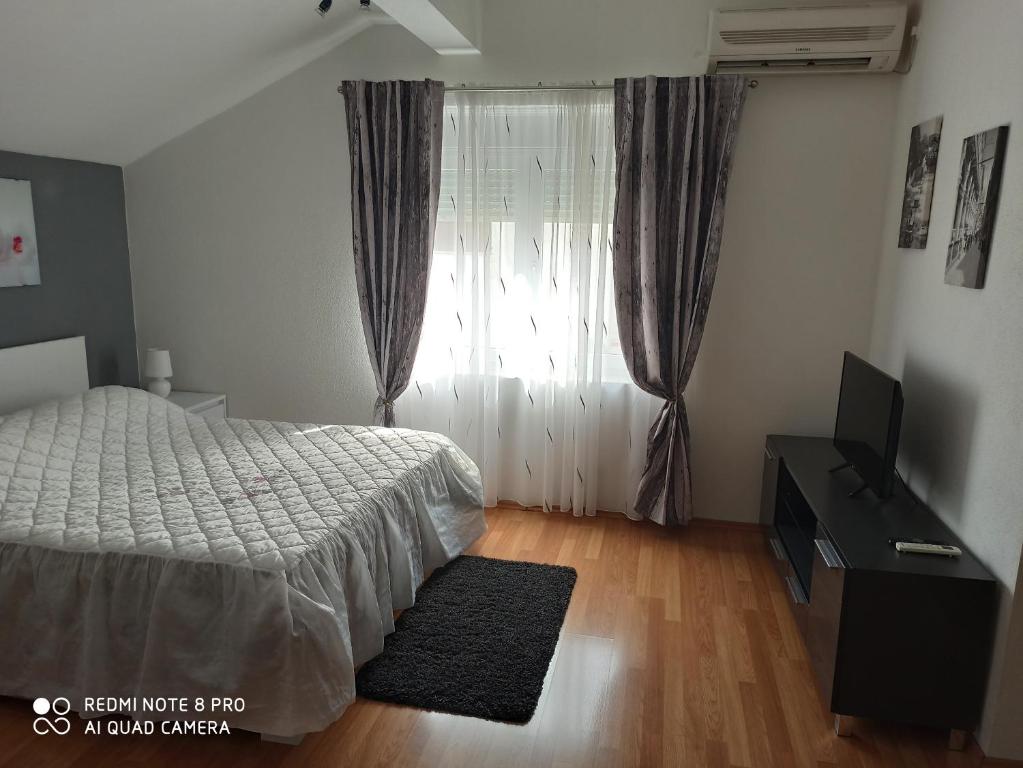 a bedroom with a bed and a dresser and a window at Apartments Roncevic in Zadar