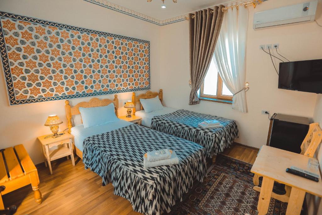 a hotel room with two beds and a tv at Yasmin in Bukhara