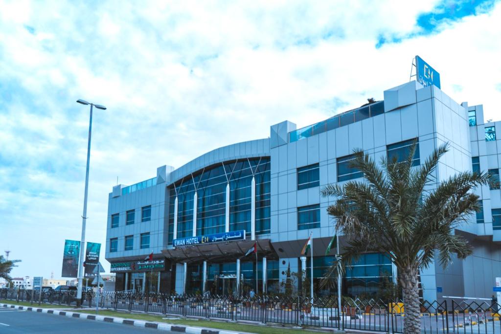 a building with a palm tree in front of it at Ewan Hotel Sharjah in Sharjah