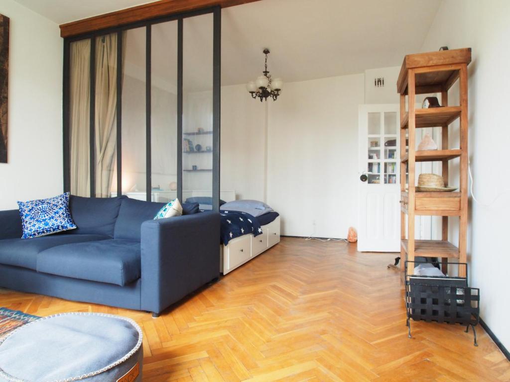 a living room with a blue couch and a bed at Grand-Tourist Apartment - Gold in Gdańsk