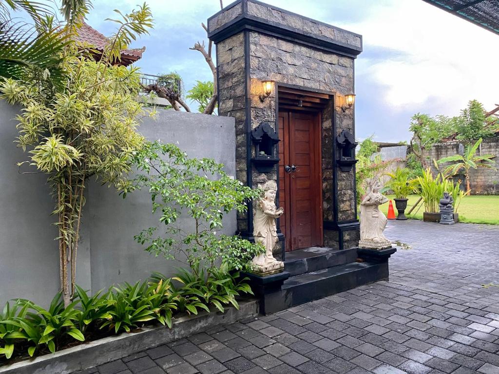 a building with a wooden door and some plants at Dikubu Belong Seminyak in Seminyak