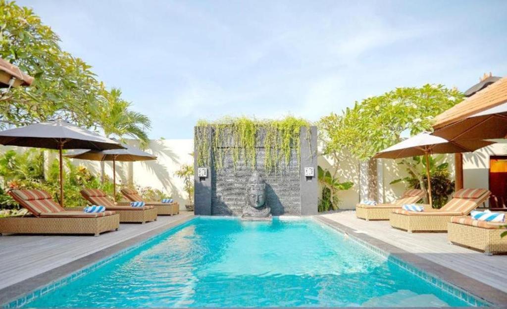 a swimming pool with chairs and umbrellas in a resort at Villa Seriska Dua Sanur with Private Pool in Sanur