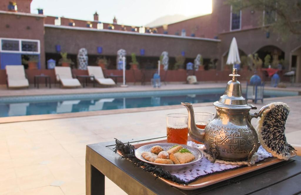 a tea kettle and a bowl of food on a table near a pool at Riad Malak in Ouirgane