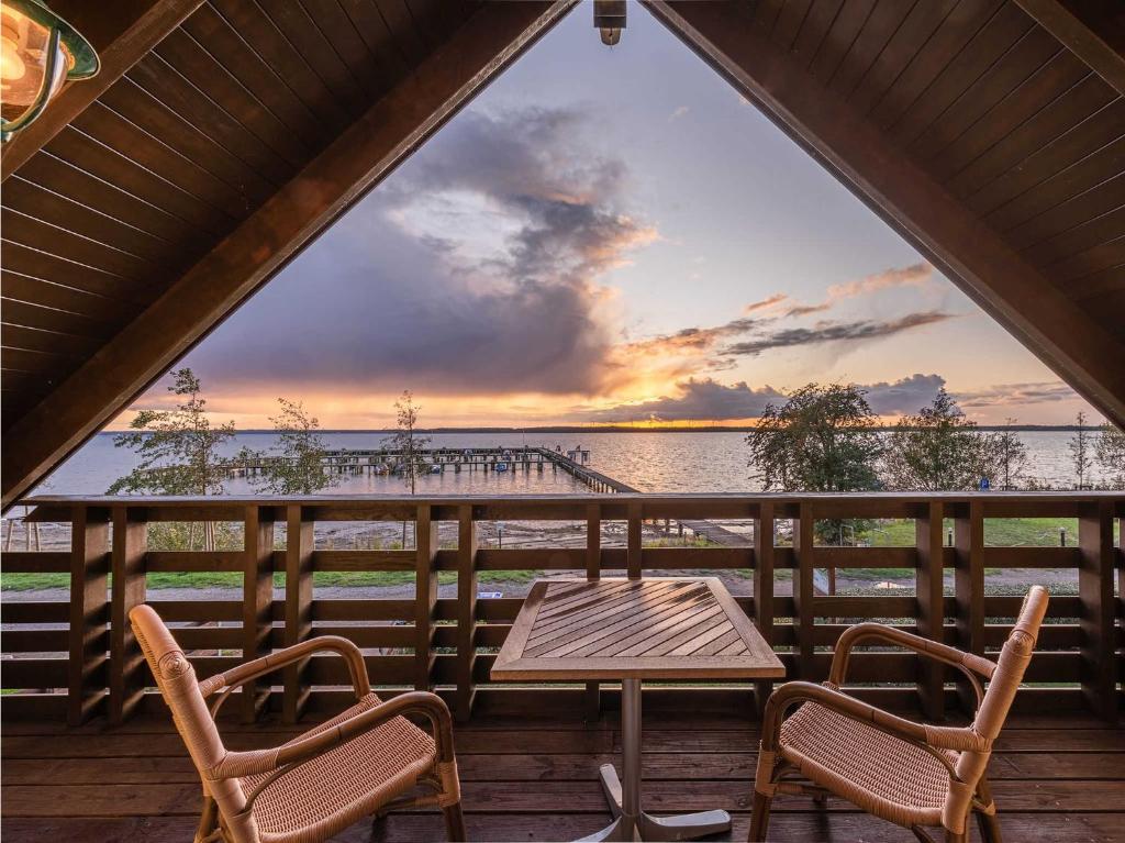 a table and chairs on a porch with a view of the water at Ferienhaus Uttied - direkt am Plauer See in Alt Schwerin