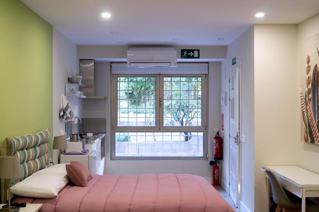 a bedroom with a pink bed and a window at Moncloa room apartments in Madrid